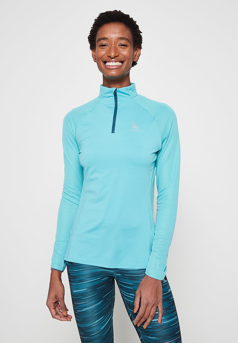 Lichtblauwe langslavige top met een kwart rits, met een gladde textuur en een aangesloten ontwerp, gecombineerd met teal patroonlegging.