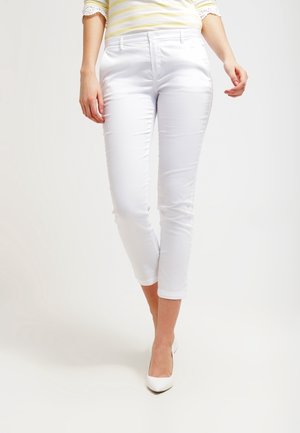 Witte cropped broek van een gladde stof, met een smalle pasvorm en zakken, gecombineerd met een licht gestreept topje en witte hakken.