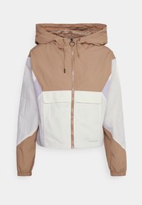 Cropped windbreaker jacket featuring a beige, white, and lilac color block design, adjustable hood, and zippered front with two pockets.