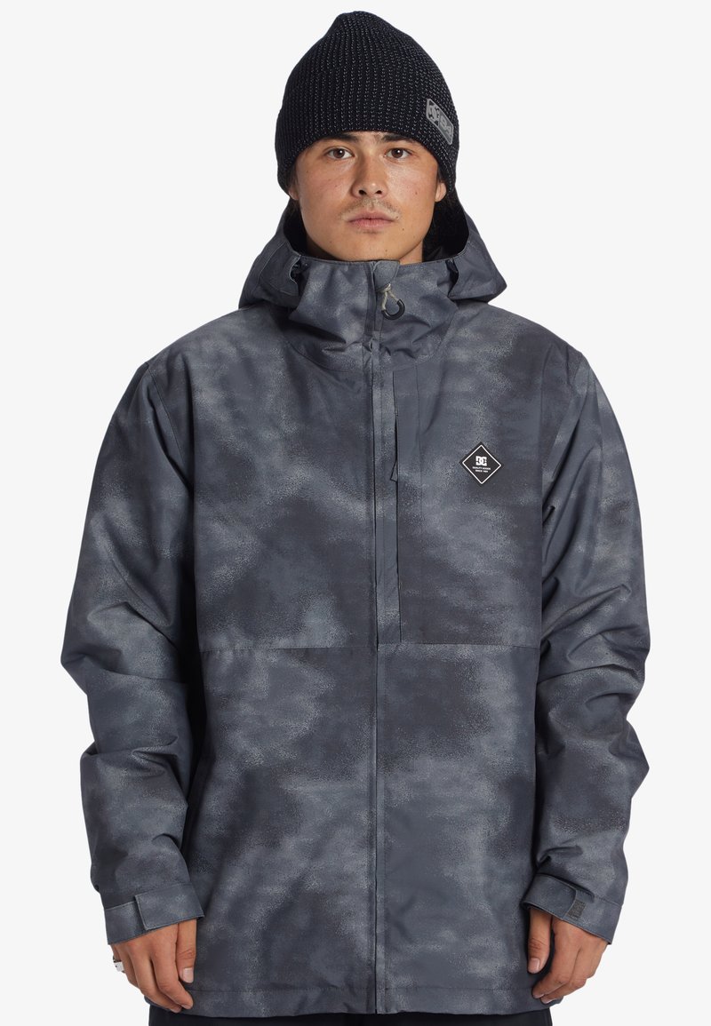 Šedá, voděodolná bunda s texturovaným, oblačným vzorem, nastavitelnou kapucí, předním zipem a logem na hrudi.