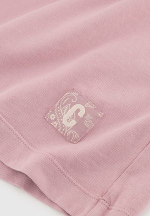 Rosa Baumwollstoff mit einer glatten Textur, verziert mit einem dekorativen Patch im paisley Muster und einem auffälligen Buchstaben 'C' in Beige.