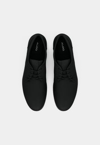 Par de zapatos casuales negros con cordones y puntera redondeada, con la marca ALDO en el interior, vistos desde arriba sobre un fondo blanco.