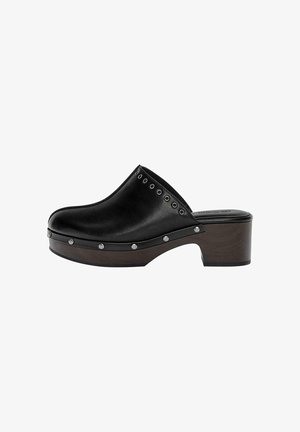 Zwarte leren klomp met een ronde punt, houten plateau en een lage blokhak. Heeft zilveren studs langs de rand voor extra detail.