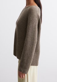 Gebreide trui in bruin met een ribbelstructuur, voorzien van een brede halslijn en lange mouwen, gecombineerd met een lichtgekleurde onderkant.