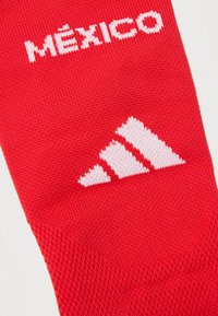 Κόκκινο πλεκτό ύφασμα με λευκό κείμενο "ΜΕΞΙΚΟ" και λευκό λογότυπο Adidas πλεγμένο στο υλικό.