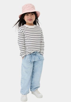 Stribet langærmet skjorte i hvid og marineblå, lyseblå denim joggers med elastisk talje, lyserødt bøttehat og hvide sneakers.