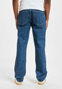 Blauwe denim jeans met een recht model, twee achterzakken en subtiele stiksels. Het materiaal lijkt duurzaam en heeft een gladde textuur.
