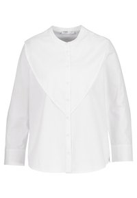 Camicia bianca con bottoni, realizzata in cotone, con colletto alto e un ampio dettaglio a flap sulla spalla arrotondata. Maniche lunghe e orlo dritto.