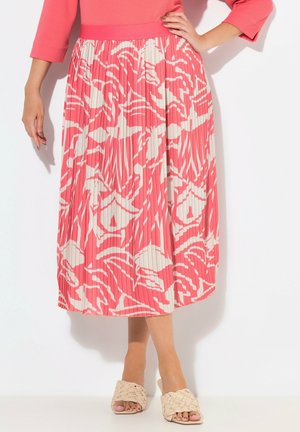 Falda midi con pliegues en coral y crema con patrón abstracto; cinturilla elástica; combinada con sandalias trenzadas beige. Textura de tejido suave.