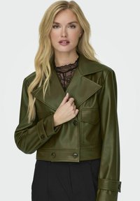 Giacca in finta pelle verde oliva tagliata, con ampi risvolti, bottoni doppi e tasche laterali. Texture con una finitura liscia.