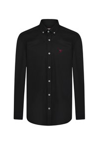 Camisa negra de manga larga con cuello abotonado, botón frontal con botones plateados y un pequeño logo de un pájaro rojo en el pecho.