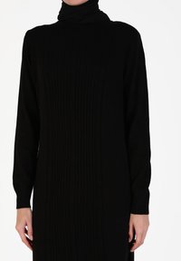 Black long-sleeve dress with a high neckline, featuring a ribbed pattern and ribbed cuffs. Made of soft, textured fabric.
