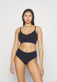 Svart to-delt undertøysett med bralette med tynne stropper og høyhalsede truser laget av mykt strikkemateriale.