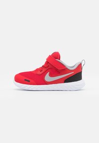 Scarpa sportiva rossa con tomaia in rete, dettagli grigi e tallone nero. Presenta una fascia in velcro e una suola bianca testurizzata per una migliore aderenza.