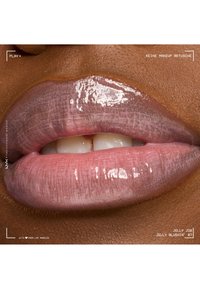 Lèvres roses brillantes avec une texture naturelle sur une peau foncée, légèrement entrouvertes montrant des dents blanches, sans retouche de maquillage visible.