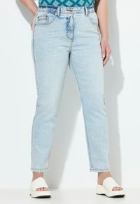 Vaaleansiniset farkut, joissa on korkea vyötärö, slim fit -malli ja hieman haalistunut pinta. Varustettu etu- ja takataskuilla, ja yhdistettyinä valkoisiin liukuvaatteisiin.