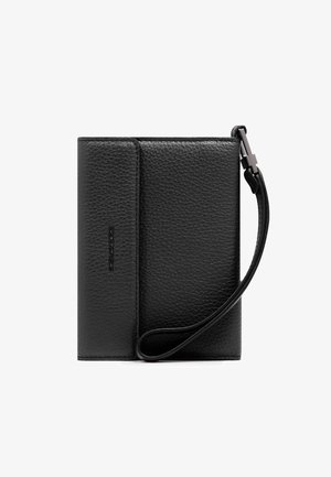 Cartera de cuero negro con textura, con una correa de muñeca sujeta por un broche metálico, plegada y cerrada, sobre un fondo blanco.