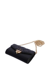 Bolso bandolera acolchado de cuero negro con una correa de cadena dorada y cierre, que presenta una textura suave y un detalle de logo en la solapa.