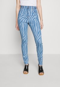 Jeans azules de tiro alto con un patrón de rayas de cebra, hechos de denim, que cuentan con un clásico diseño de cinco bolsillos y un cierre de cremallera/botón.
