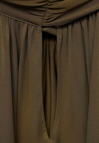Olive green dress fabric with a textured finish. Gathered top with a keyhole opening, flowing pleats beneath.