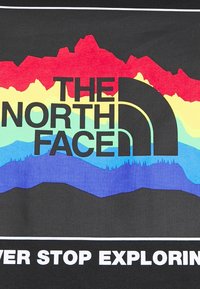 Graphic t-shirt featuring "The North Face" logo in bold black, with multicolored mountain range design in red, yellow, green, blue on black background.