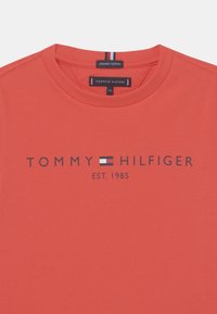Koralfarvet T-shirt i �økologisk bomuld med rund halsudskæring, med teksten "TOMMY HILFIGER EST. 1985" trykt i mørk navy, samt et lille logo som accent.