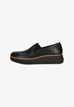 Black leather slip-on shoes featuring a slightly elevated, textured outsole and a contrasting brown midsole for added detail.