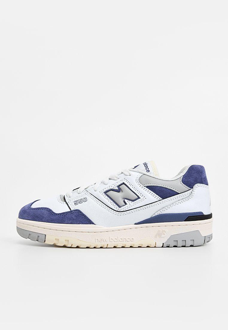Baskets blanches et violettes avec un upper en cuir texturé et en daim, comportant une semelle en caoutchouc grise, un laçage à l'avant et un détail du logo New Balance.