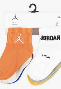 Šest parov nogavic do gležnjev v oranžni, beli, modri in rumeni barvi z pleteno teksturo. Ena nogavica ima Jordanov logotip, druga pa ima natiskan napis "JORDAN".