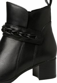 Černé kožené kotníkové boty s pleteným páskem, mírným podpatkem a prošíváním na svršku. Hladký povrch s strukturovaným designem.