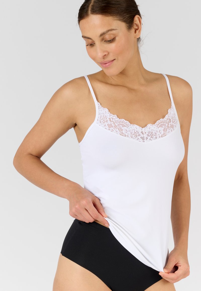 Witte top met kant langs de halslijn, dunne bandjes en een gladde, zachte textuur. Gecombineerd met zwarte onderbroek met hoge taille.
