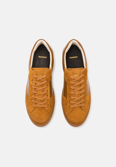 Kohvipruun suede spordijalatsid nahkdetailidega, ümmargune ninaosa ja beežid paelad. Must ja kuldne "SANDRO" bränding keelel.
