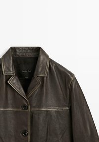 Brun læderjakke med notched krave, knaplukning og en glat tekstur med en subtil glans. Label synlig inde i kraven.