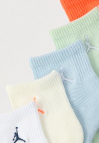 Πέντε ζευγάρια κοντές κάλτσες σε πορτοκαλί, πράσινο, μπλε, άσπρο και κίτρινο. Κάθε ζευγάρι διαθέτει ένα λογότυπο σε αντίθεση στη μανσέτα. Ριγωτή υφή σε όλο το μήκος.