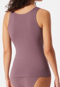 Paarse tanktop gemaakt van zacht materiaal, met dunne schouderbandjes, een ronde halslijn en een getailleerde pasvorm met subtiele stikseldetails.
