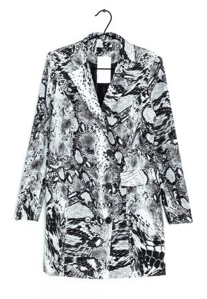 Blazer à manches longues imprimé serpent noir et blanc avec col à revers, fermeture par boutons et poches à rabat, accroché à un cintre noir.
