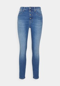 Blå denim skinny jeans med hög midja, med fem metallknappar och subtila blekningar, vilket skapar en slät textur och en figurnära form.