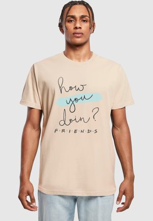 Beige short-sleeve t-shirt featuring a graphic design with text "how you doin'?" and "F.R.I.E.N.D.S." in black and light blue colors.