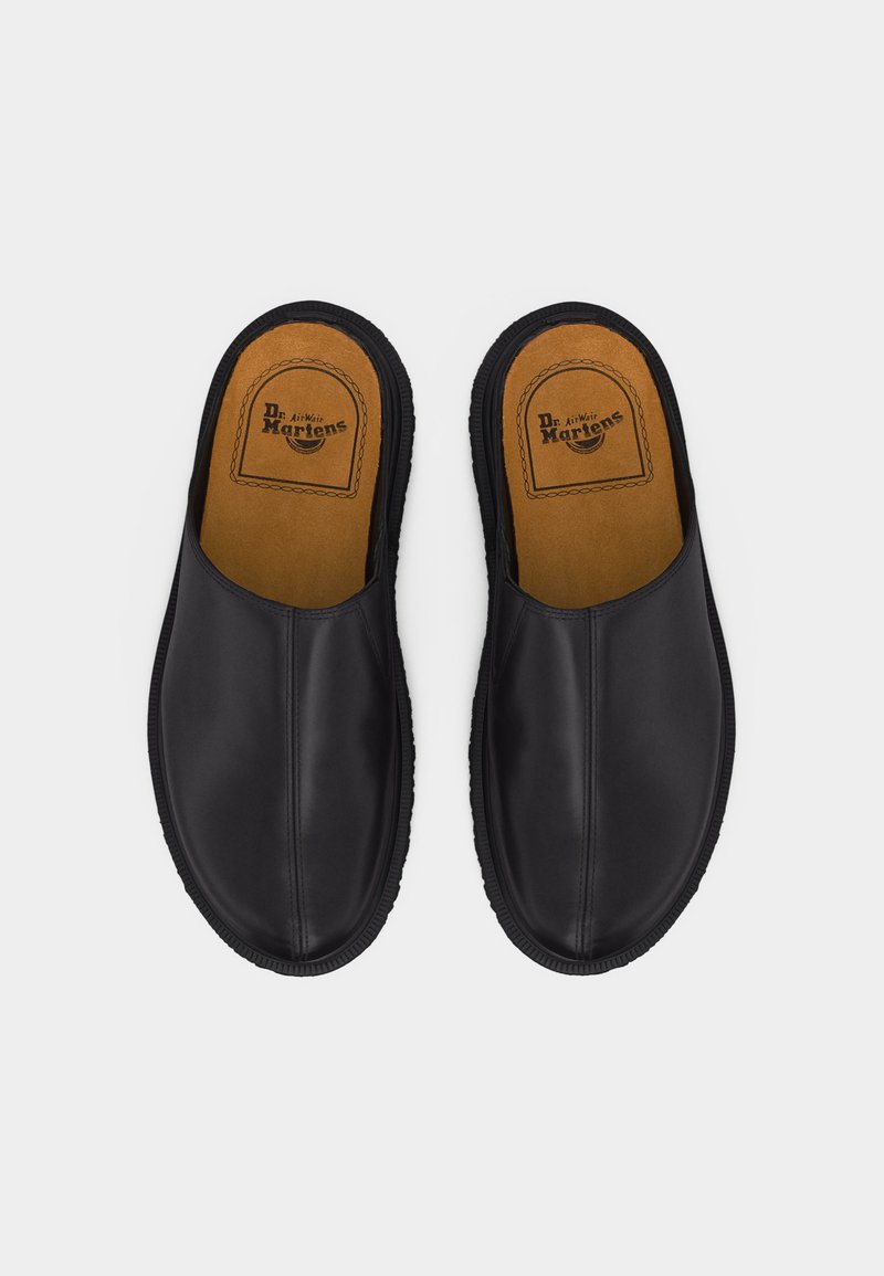 Scarpe Dr. Martens nere in pelle con chiusura a infilare, suole interne marroni e logo del marchio visibile, viste dall'alto su uno sfondo bianco.