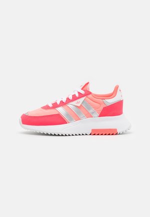 Niski sneaker w kolorze koralowego różu i srebra z białymi sznurowadłami, trzema paskami Adidas oraz grubą białą podeszwą z teksturowanym bieżnikiem.