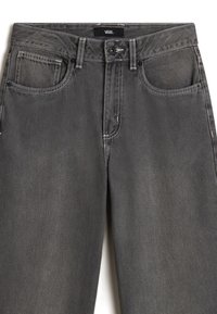 Jean en denim gris foncé avec poches avant, passants pour ceinture, fermeture par bouton et coutures blanches visibles, marque Vans sur la ceinture.