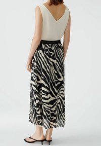 Robe plissée avec un motif zèbre noir et crème. Le haut présente un dos en V, et la taille est élastique avec une bande contrastante.