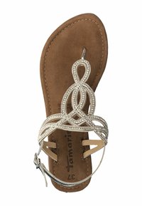 Platte sandaal met een tan kleurige faux suede voetbed, zilveren decoratieve band met verweven lussen en een dunne enkelband met een gesp.