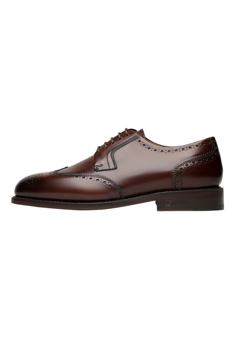 Scarpa da uomo in pelle marrone con dettagli brogue, punta rotonda e allacciatura a cinque fori, poggiata su una suola piatta e testurizzata.