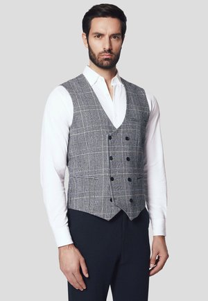 Szary kamizelka w kratę z sześcioma czarnymi guzikami, z klapami i dopasowanym krojem, noszona na białej koszuli i zestawiona z ciemnymi spodniami.