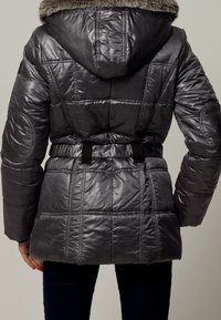 Giacca a vento grigia imbottita con cappuccio e trim in pelliccia sintetica. Presenta una vita con cintura e un design trapuntato con linee orizzontali e maniche textured.