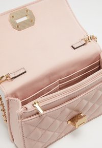 Borsa a tracolla rosa trapuntata con accenti dorati, dotata di chiusura magnetica, tasca con zip e tracolla a catena. Interno in tessuto morbido.