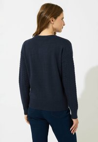 Suéter de marina con mangas de punto trenzado texturizado y dobladillo acanalado. Corte estándar, escote redondo y cuerpo liso.