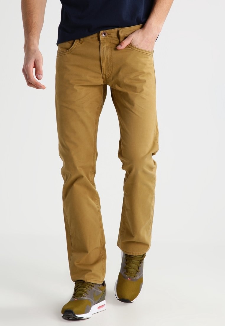 Beige bomulls chinos med rak passform, utrustade med fem fickor och diskreta sömmar. Bärs med sportskor i grått och grönt.