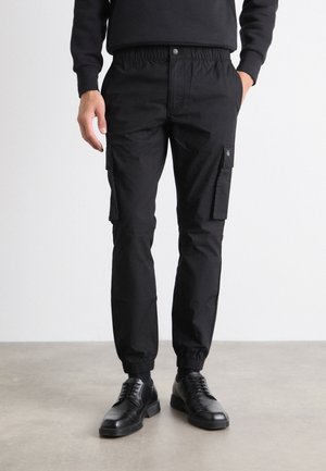 Sorte cargo bukser lavet af holdbart stof, med elastisk talje, tapered manchetter, sidelommer og et sort logo mærkat.